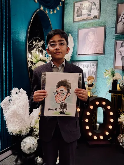 A young guest looking sharp and holding his personalized caricature at a beautifully decorated evening party.