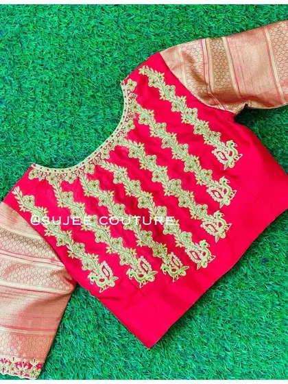 A vibrant red blouse with contrasting gold brocade sleeves. The body of the blouse features vertical lines of gold zardozi embroidery, creating a unique pattern.