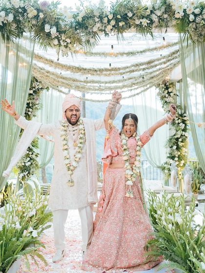 The couple raises their hands in celebration after their wedding ceremony, a moment of pure triumph and joy.