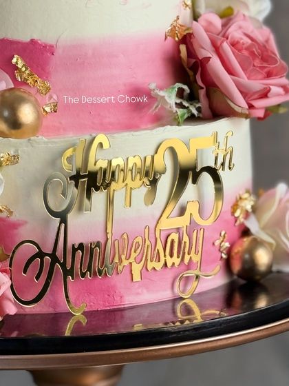 A close-up of the beautiful gold "Happy 25th Anniversary" topper on the elegant pink ombre cake.