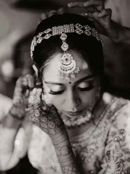 A black and white shot of the bride getting ready, focusing on the details of her jewelry and makeup.