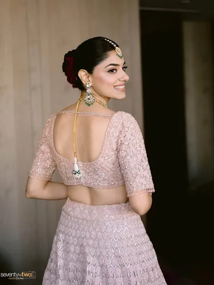 A beautiful back profile of the bride, showing off her elegant hairstyle and the delicate details of her blouse.