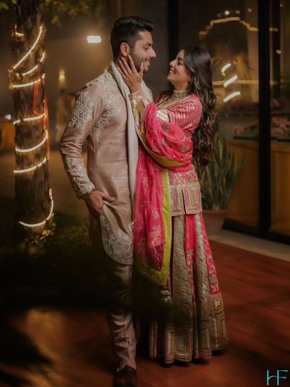 A sweet and romantic portrait of the couple, the bride gently touching the groom's face, set against a backdrop of twinkling lights.