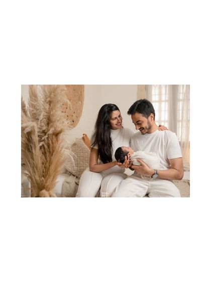 The beauty of new beginnings, with new parents gazing lovingly at their swaddled baby in our bright and airy boho set.