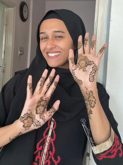 A lovely photo of a happy client and influencer showing off her simple and elegant floral henna. Her smile says it all.