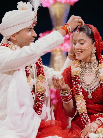 The sindoor ceremony is a deeply significant and emotional ritual. This photo captures the gentle intimacy of the moment, with the groom's careful gesture and the bride's serene smile.
