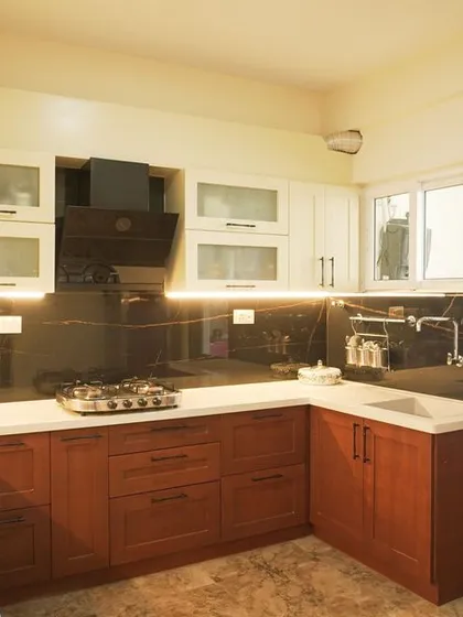 We designed this classic U-shaped kitchen with a two-tone scheme, featuring rich, shaker-style wooden base cabinets and clean white overhead units. This combination creates a timeless look, complemented by a white quartz countertop and under-cabinet lighting for a bright and functional workspace.