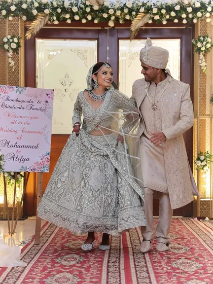 The happy couple making their entrance. The bride's silver-white lehenga and matching diamond jewellery create a breathtaking, coordinated look.