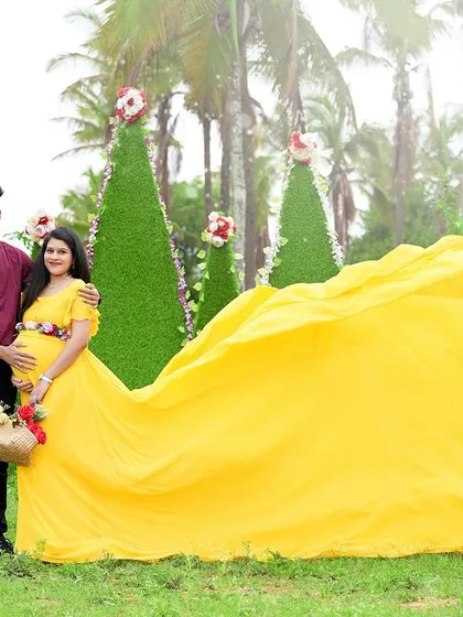 A dramatic flying gown shot. The vibrant yellow fabric of the dress creates a stunning visual against the green landscape, making for a truly memorable maternity photo.