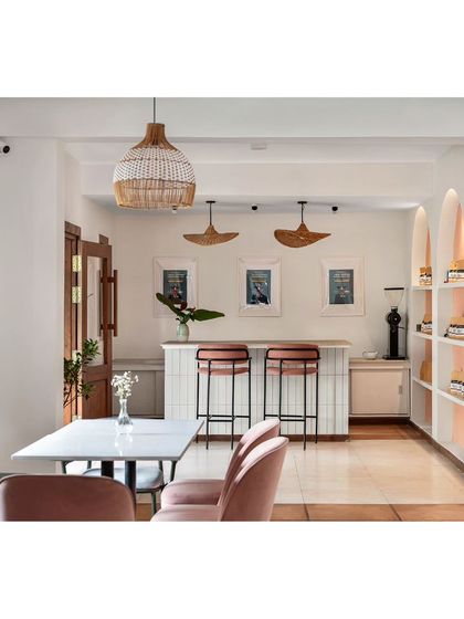 An overview of the upper floor at Kana Cafe, designed as a quiet indoor dining space. The minimal furniture and pastel color palette create a calm ambiance that contrasts with the open-air ground floor.