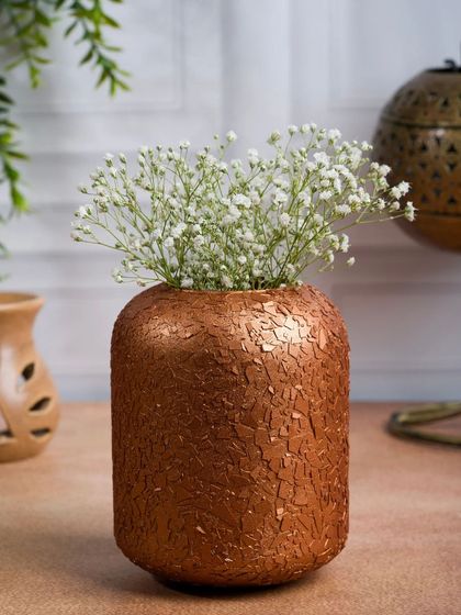 A textured copper vase filled with baby's breath. The focus here is on the unique texture of the vase, highlighted by careful lighting.