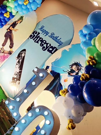 A cool Skateboard-themed 10th birthday party. The decor features skateboard-themed backdrops, a blue and green balloon garland, and a large light-up number '10'.
