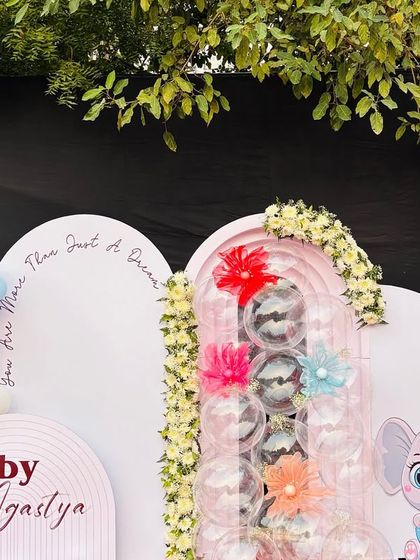 A sweet and modern backdrop for Baby Agastya's Kuan Pujan ceremony. The setup features pastel-colored balloon garlands, a cute elephant cutout, and personalized text on arched panels.