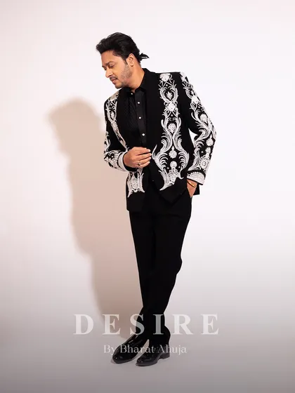 A side profile showcasing the impeccable fit and intricate embroidery of the black statement blazer. Every angle is designed to impress.
