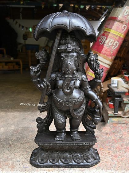 A unique 36-inch standing Ganesha holding an umbrella, symbolizing protection and sovereignty. This statue is available in both a dark black and a rich brown finish.