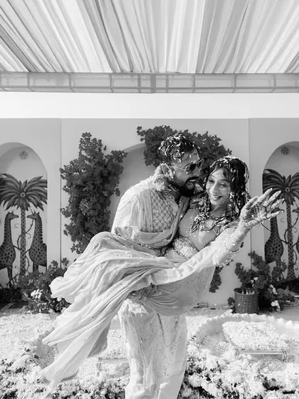A timeless black and white shot of the groom lifting the bride amidst the Haldi chaos, capturing the romance within the fun.