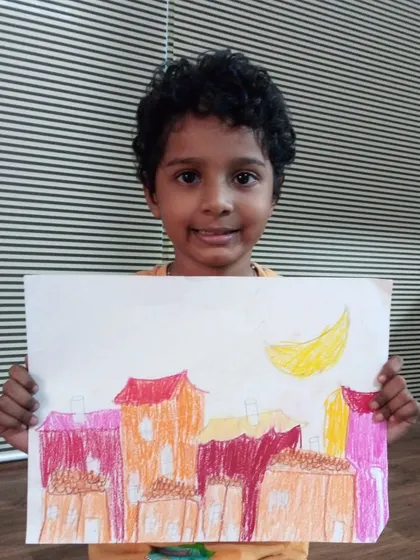 Myron, a 2nd standard student, drew this cityscape at night. He used oil pastels to create a warm, colorful scene with a crescent moon in the sky.