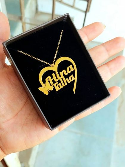 This image shows the popular heart-shaped couple's name pendant from a different angle. The butterfly detail adds a touch of delicate charm to the personalized design.