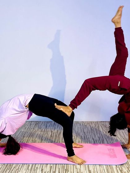 This advanced partner yoga pose combines a wheel pose with a one-legged variation, requiring immense trust, balance, and strength from both partners. It's a beautiful expression of connection.