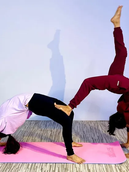 This advanced partner yoga pose combines a wheel pose with a one-legged variation, requiring immense trust, balance, and strength from both partners. It's a beautiful expression of connection.