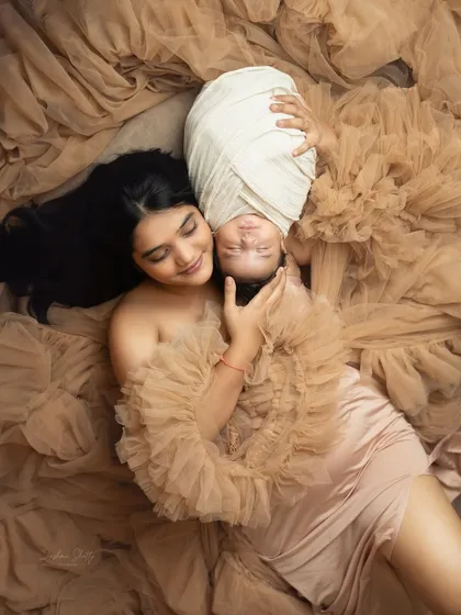 An artistic overhead shot of a mother and her baby, enveloped in flowing fabric. This type of creative portrait is a beautiful way to celebrate the bond of motherhood.