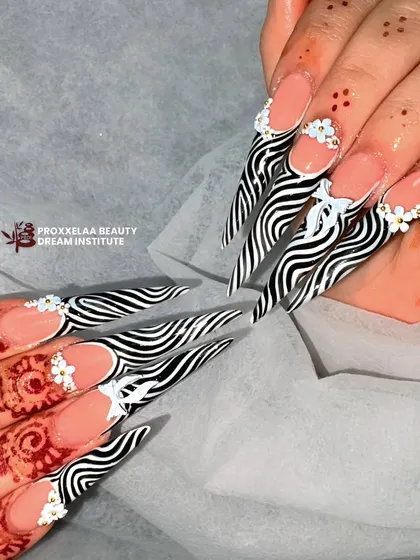We teach you to go from basic to bold. This fierce stiletto nail set with a zebra print and 3D floral accents shows the level of advanced nail technology and artistry our students learn to master.