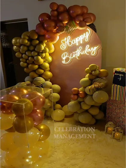 An autumn-toned balloon garland against a pink arch backdrop. The mix of mustard, beige, and metallic rose-gold balloons creates a warm and inviting look.