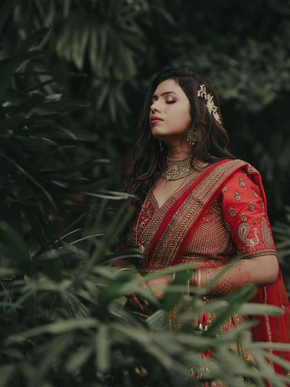 Picture perfect. This reception look is straight out of a fairytale, with the bride looking serene and beautiful in her red lehenga amidst a lush green backdrop.