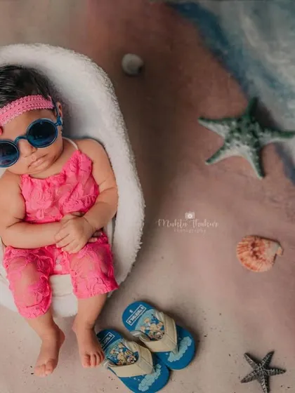 This little beachgoer is ready for her close-up, looking cool and relaxed in her sunglasses and pink lace outfit.