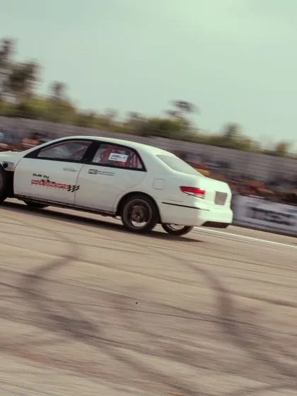 A white modified sedan battles it out with another car on the strip.