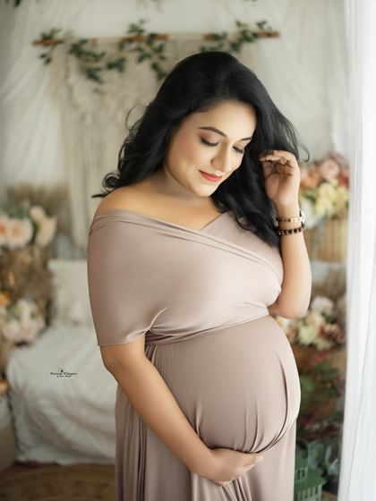A soft and dreamy portrait by the window. The natural light illuminates the mother-to-be, creating an ethereal and gentle mood.