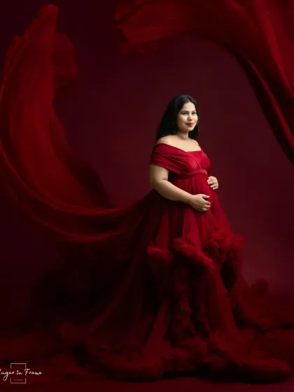 A dramatic and elegant solo maternity portrait. The flowing red gown and rich backdrop create a powerful, artistic image that celebrates the beauty of pregnancy.