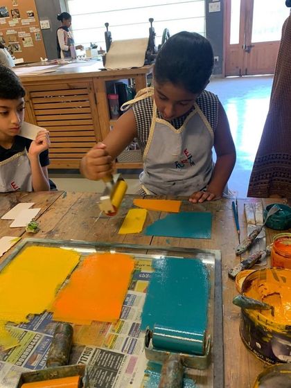 This young artist is experimenting with color by rolling different inks onto small plates. This is part of a monoprinting exercise where he will use these shapes to build a larger collage style artwork.
