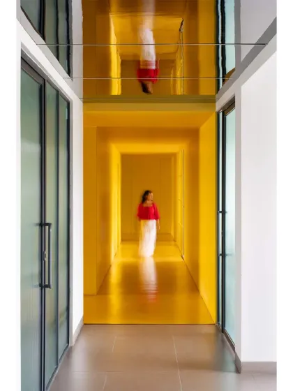 A moment of motion and reflection in 'The Amber Encase' clubhouse, where a bold, monochromatic yellow corridor creates an immersive experience. We used a mirrored ceiling to amplify the sense of height and play with perception, turning a simple passageway into a memorable architectural feature. This demonstrates our approach to using color to define and energize public spaces.