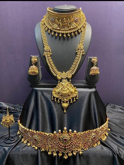 A stunning antique gold bridal set with a statement choker and a matching long necklace. The intricate details and the central deity motif make this a very special set for your big day.