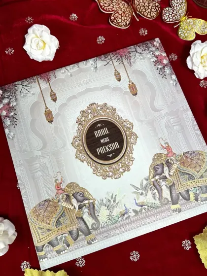 This invitation combines elegance and tradition, featuring two caparisoned elephants and an ornate central frame on a silver-white background.