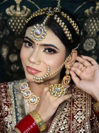 Adjusting the earring, this shot captures the intricate details of the bridal jewelry and the flawless makeup application. You will learn how to style the entire look, not just the face.