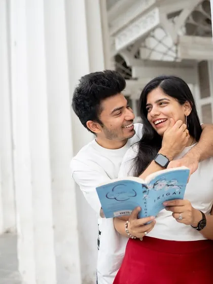 A sweet, interactive moment during a pre-wedding shoot at a classic Mumbai location. Using props like a book can help tell a more personal story about the couple's interests.
