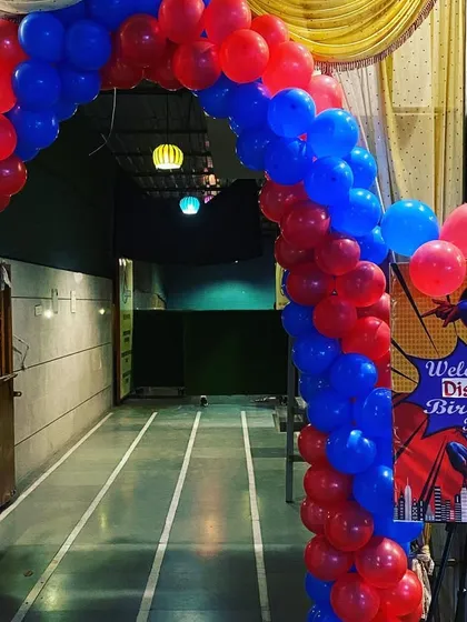 A grand entrance for a Spiderman-themed birthday party, featuring a red and blue balloon arch and a custom welcome sign.