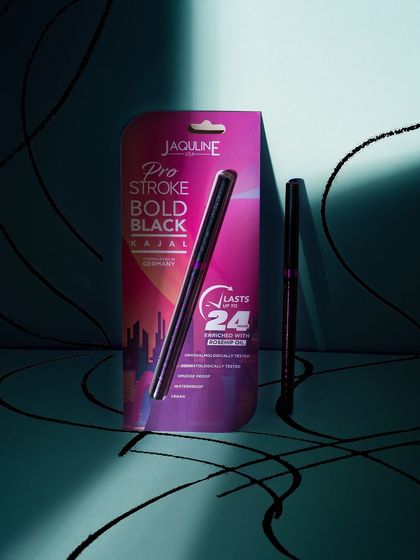 A dramatic shot of a kajal pen and its packaging, using shadows and light to create a moody and bold look.