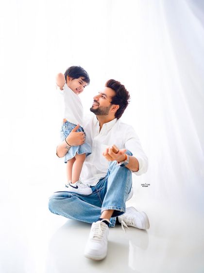 A candid moment of laughter between father and son. The simple white shirts and jeans keep the focus on their genuine connection.