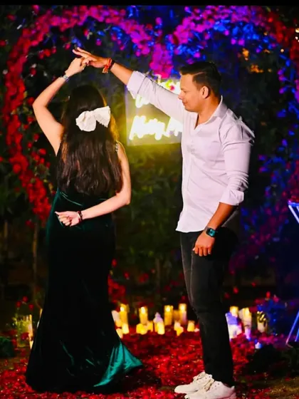 The newly engaged couple sharing a dance. The ambient lighting from the candles and the floral heart arch creates a dreamy, cinematic feel.