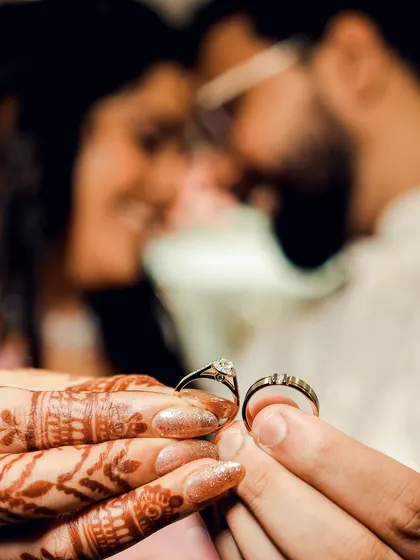 A creative shot of the engagement rings, held by the couple with their faces softly blurred in the background. This photo beautifully symbolizes that their union is at the heart of the celebration.