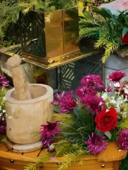 A rustic decor element featuring a wooden mortar and pestle surrounded by vibrant purple and red flowers, adding a unique, traditional touch to the setup.