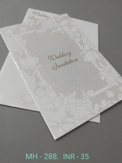 A white invitation with a subtle floral embossed frame. This card is simple, elegant, and very affordable, perfect for a classic wedding announcement.