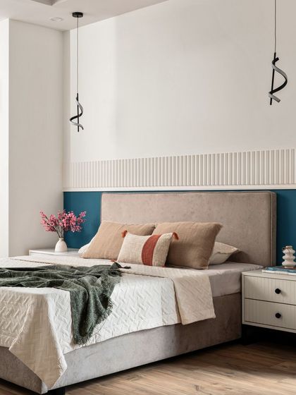 This bedroom design is all about beauty in simplicity. The back wall features a two-tone design with a bold teal panel below a section of white fluted molding, creating a minimalist yet elegant look.