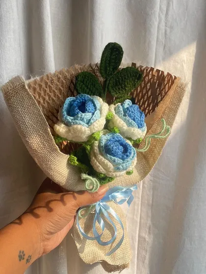 The finished blue and white rose bouquet, wrapped in burlap and tied with a blue ribbon. A simple and elegant arrangement.