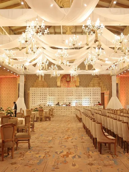A grand ballroom setup with a ceiling of flowing white drapes and dozens of crystal chandeliers, creating a dreamy, ethereal atmosphere.