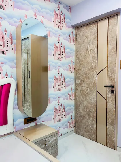 A finished kids' bedroom, showing the custom dressing table with a pill-shaped mirror and the matching marble-laminate door. The castle-themed wallpaper sets a magical tone.