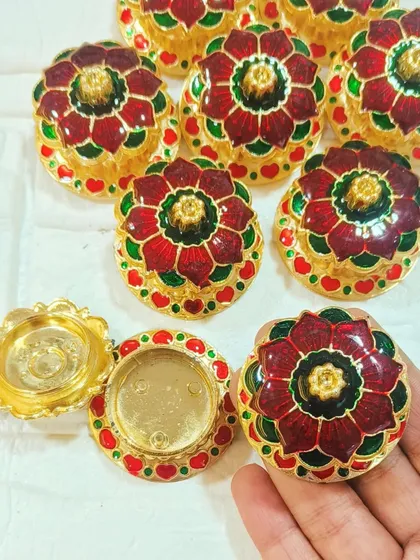 These small, ornate decorative boxes are perfect for holding kumkum or other small items on a pooja thali. Their detailed Meenakari-style design adds a colorful and traditional element to your festive setup.